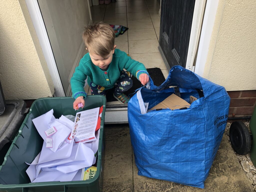Photo showing a little boy learning about sustainable living by helping to sort household recycling.