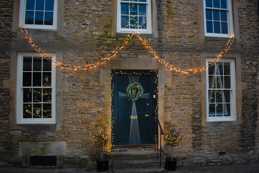 Photo of a black front door with a Christmas wreath hanging on it in Lacock Village, one of the places you can visit using your National Trust Annual Membership.