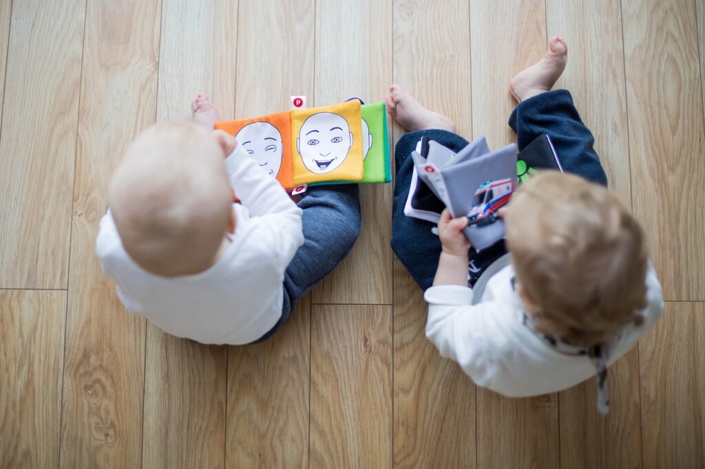 Start promoting a love of reading early: Photo of two toddler from above. They are both clutching books.