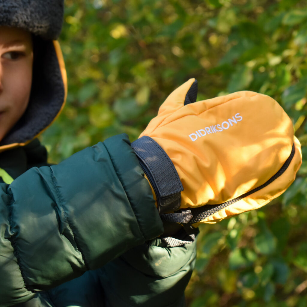 Photo of a young boys hands wearing a pair of yellow mittens. Older children can get involved in choosing their own kit for the great outdoors.