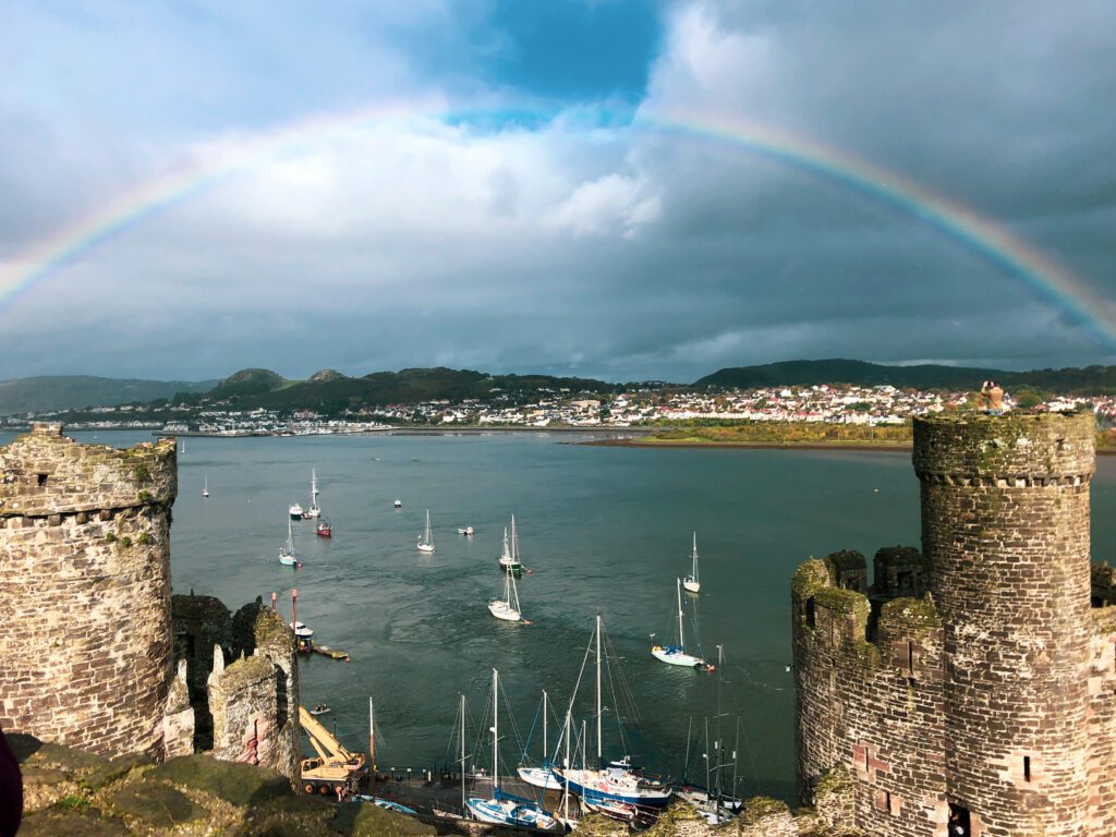 Photo of the turrets of Conwy Castle with a rainbow in the background. One of the outdoor Adventures  in and around North Wales.